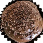 Delicious Bolo de Brigadeiro Cremoso, a rich chocolate cake decorated with brigadeiro balls and chocolate sprinkles.