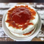Overhead shot of a cake frosted with white frosting and decorated with red crumbs.