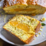 Slice of moist orange and tangerine loaf cake with poppy seeds and a sweet glaze.