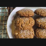 Close-up of a cooling rack filled with vegan ginger and cinnamon cookies, sprinkled with sugar.
