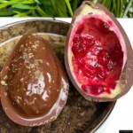 A large chocolate Easter egg, opened to reveal a rich chocolate interior, next to its unopened box.