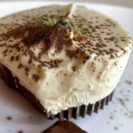Close-up of a Semifreddo de Matcha e Chocolate Branco, a pale green dessert with a dark chocolate cup and garnish.