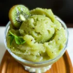 Close-up of a small bowl of refreshing kiwi sorbet, a wooden spoon scooping a portion.