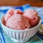 A scoop of light pink watermelon basil sorbet in a small white bowl.